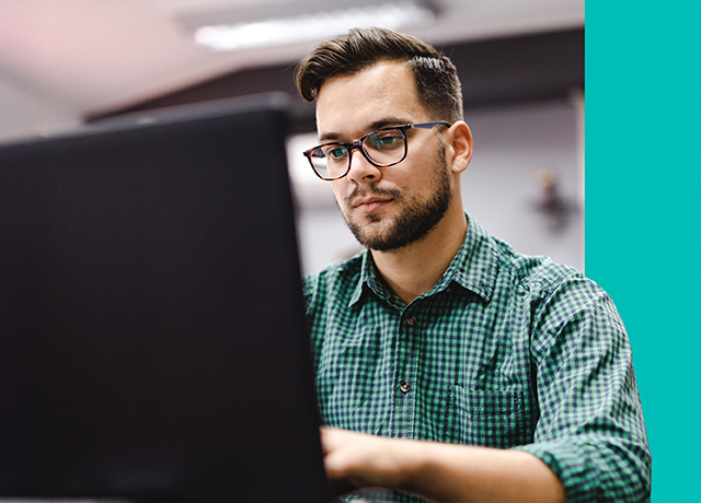 Person working on a laptop in a classroom, representing online English testing.